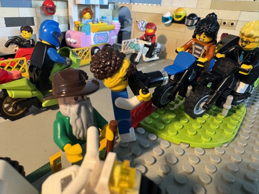 Fedde en Jip zitten op motoren op de motorbeurs. Wapke maakt een foto